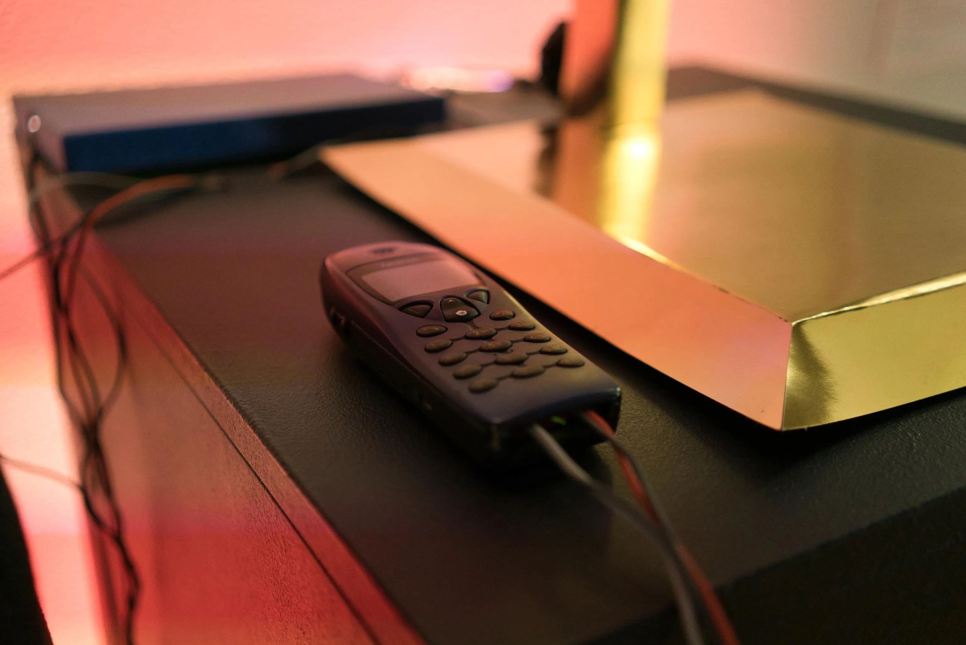 An old phone lying next to a golden pedestal.