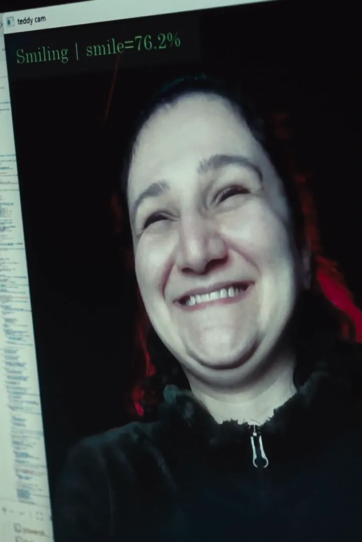 A web camera view of a person smiling widely, text saying 'smiling'.