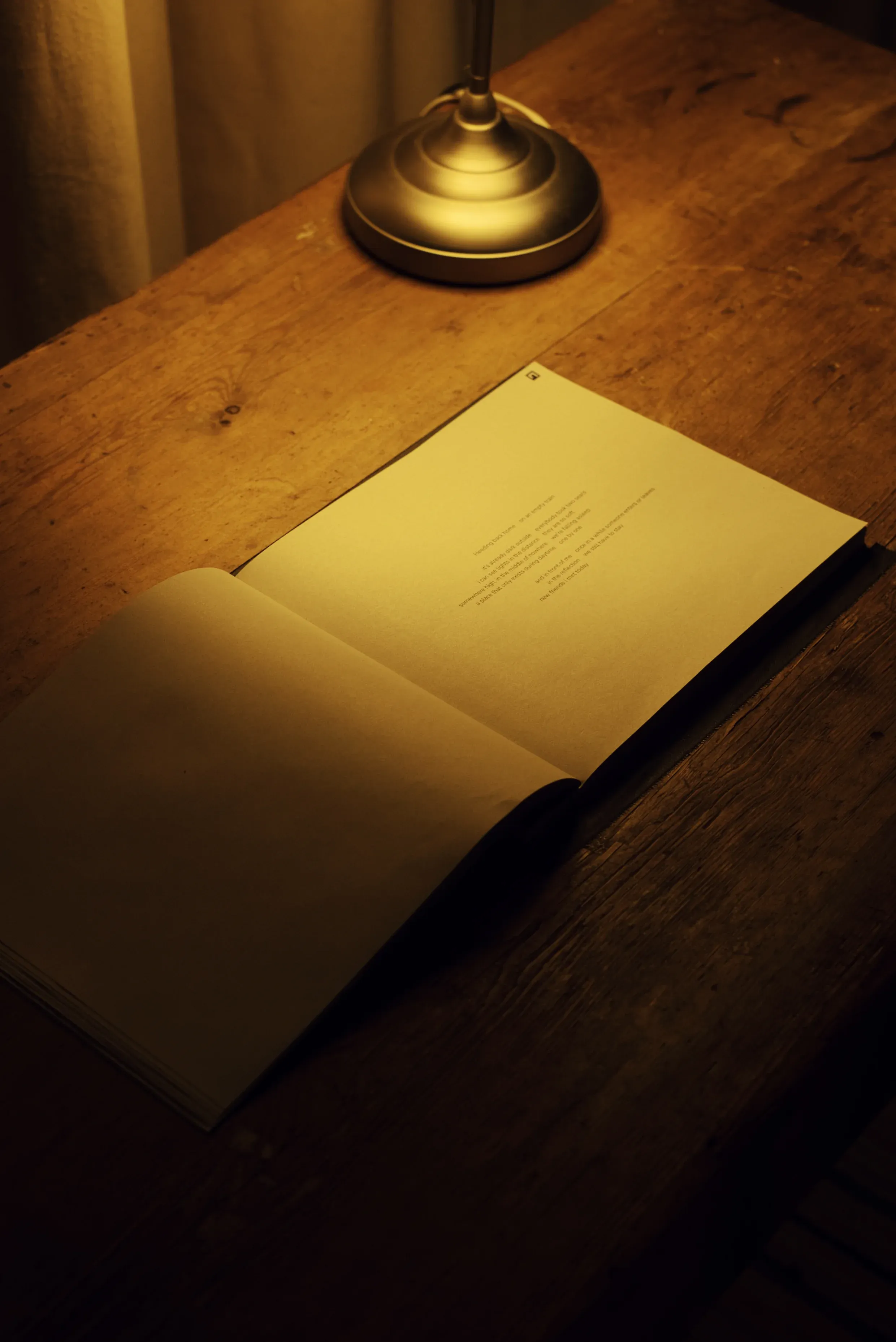 An open book on a wooden table under a light.
