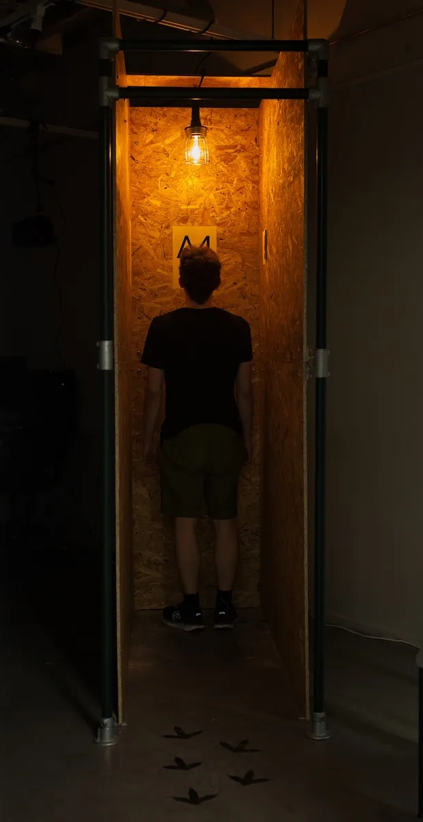 A person standing inside a wooden chicken cage.